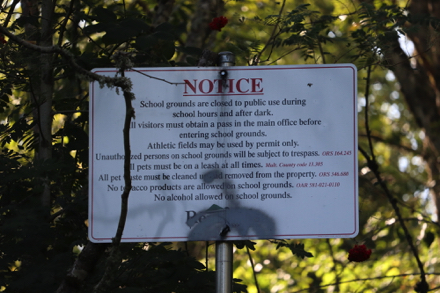 Sign with written notice in regards to Arata Creek School which borders the park